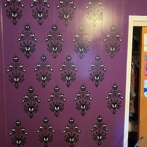 May include: A purple wall with a repeating pattern of black silhouettes of ghosts with white eyes. The pattern is reminiscent of the Haunted Mansion at Disneyland.
