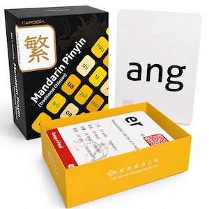 May include: A Mandarin Pinyin learning card set in a black and yellow box. The box displays the text Mandarin Pinyin Traditional Chinese and various pinyin syllables. One white card shows the text ang, and another card shows er.
