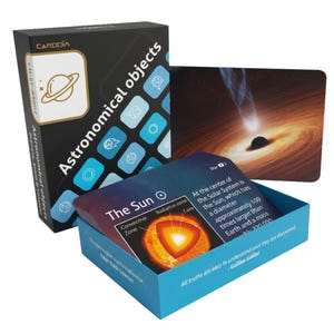 Può includere: Una scatola di gioco educativo Cardia intitolata Astronomical objects, con un design nero e blu con icone di elementi spaziali. La scatola aperta mostra carte con immagini del Sole e di un buco nero, inclusi testo descrittivo e diagrammi.