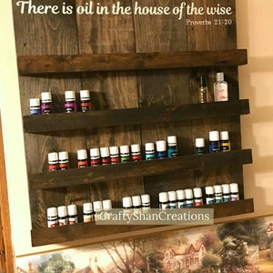 May include: A wooden shelf with four shelves for storing essential oils. The shelf has a sign that reads "There is oil in the house of the wise Proverbs 21:20".