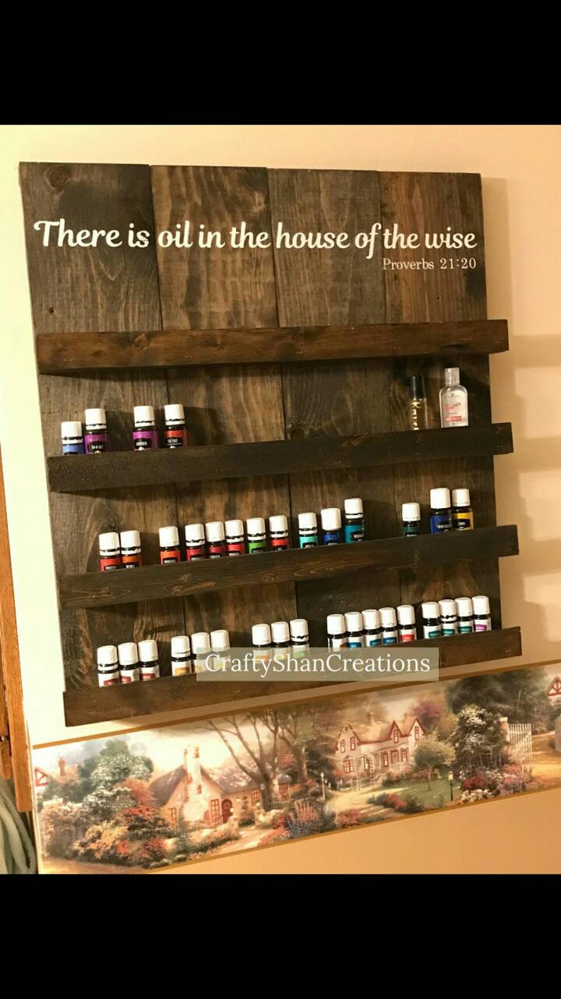 May include: A wooden shelf with four shelves for storing essential oils. The shelf has a sign that reads "There is oil in the house of the wise Proverbs 21:20".