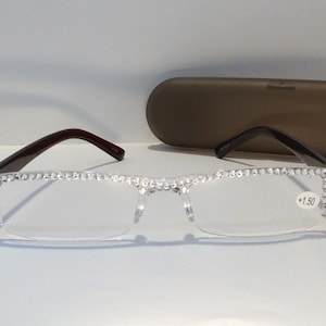 May include: Clear reading glasses with a rhinestones frame and brown temples. The glasses have a +1.50 magnification.