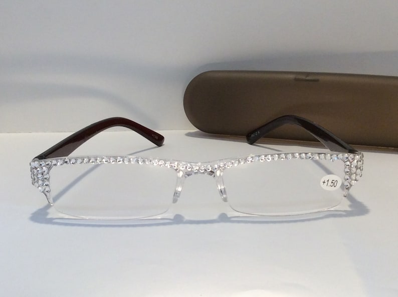 May include: Clear reading glasses with a rhinestones frame and brown temples. The glasses have a +1.50 magnification.