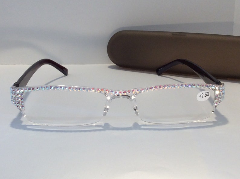 May include: Clear reading glasses with a black frame and rhinestones around the edges. The glasses have a +2.50 lens strength.