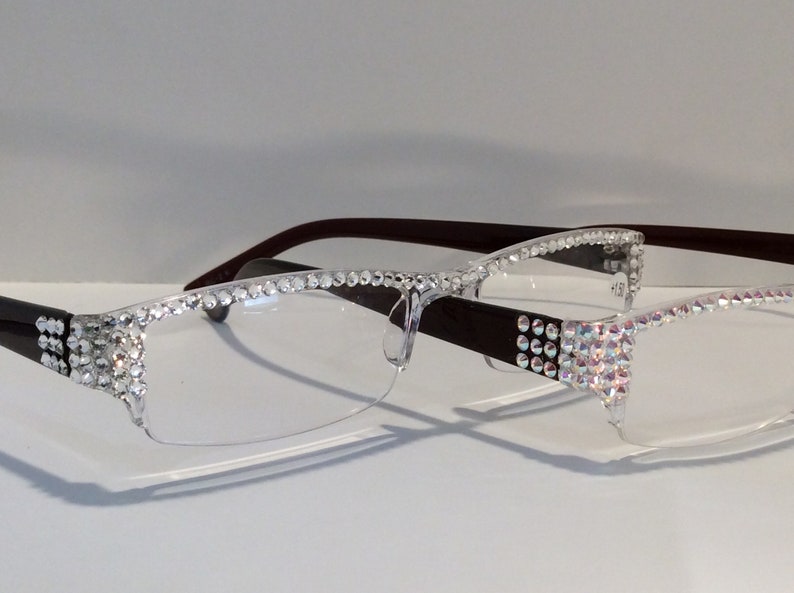 May include: A pair of clear glasses with a brown frame. The frame is decorated with rhinestones.