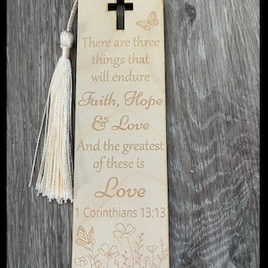May include: Wooden bookmark with a cross, butterfly, and floral design. It features the quote "There are three things that will endure Faith, Hope & Love And the greatest of these is Love 1 Corinthians 13:13".
