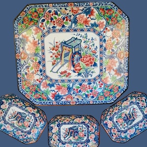 May include: A set of four decorative ceramic plates with a floral design. The plates are blue, white, and pink with a floral pattern. The largest plate is octagonal and the three smaller plates are rectangular.