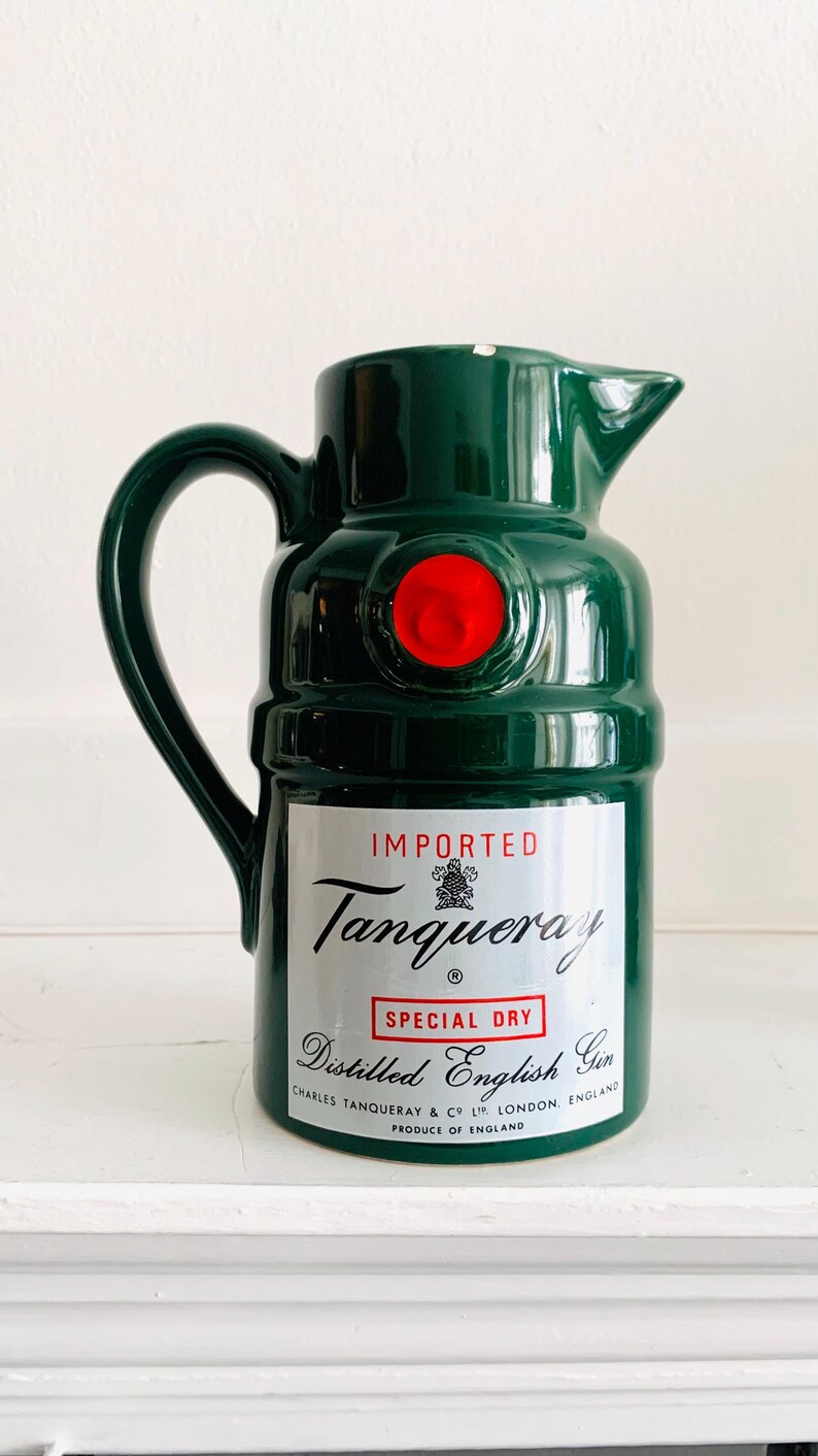 May include: A green ceramic pitcher with a handle and spout, featuring a red circular accent. The pitcher has a label that reads "IMPORTED Tanqueray SPECIAL DRY Distilled English Gin."
