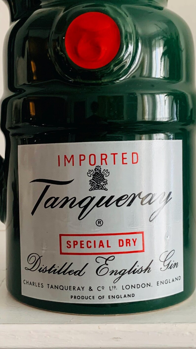 May include: A green ceramic bottle with a red top. The label reads "IMPORTED Tanqueray SPECIAL DRY Distilled English Gin." The bottle is from Charles Tanqueray & Co Ltd, London, England. The product is made in England.
