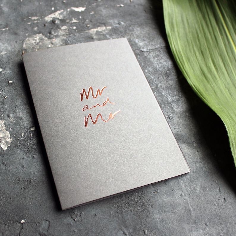 May include: A gray card with the words "Mr and Mr" written in copper foil.