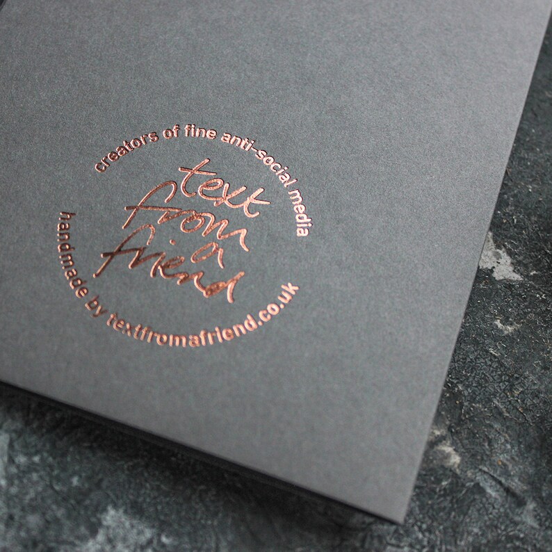 May include: A black card with a copper-colored circle containing the text "text from a friend" and the words "creators of fine anti-social media handmade by textfromafriend.co.uk".