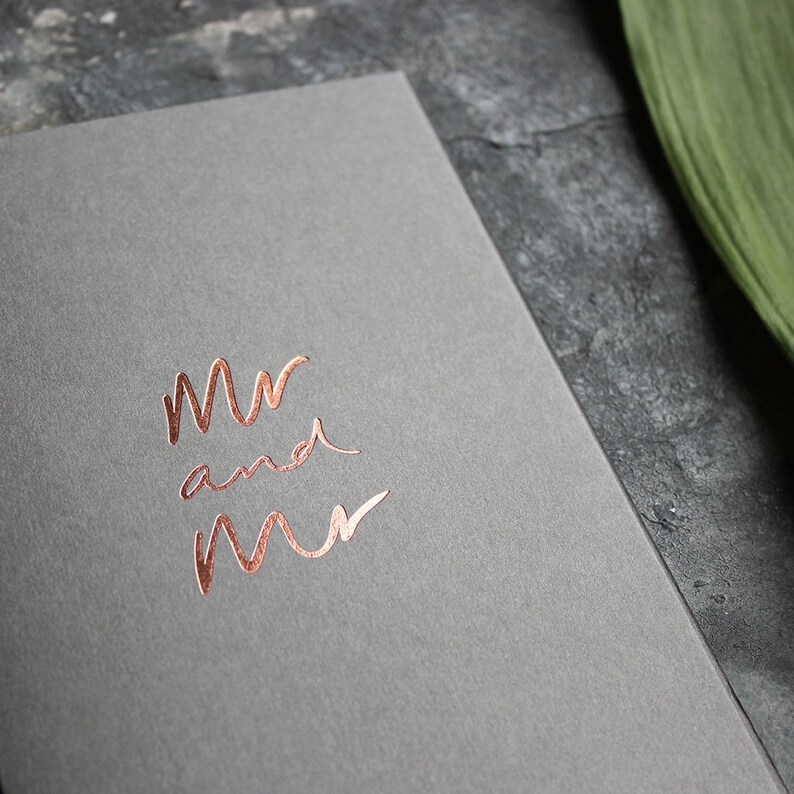 May include: A gray card with the words "Mr and Mr" in copper foil lettering.