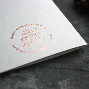 May include: A white card with a rose gold circle logo that says "creators of the anti-social media text from a friend handmade by textfromafriend.co.uk"