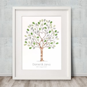 May include: A white framed print featuring a watercolour illustration of a tree with green and grey leaves. The tree has a heart-shaped opening in the branches. The text "Daniel & Jana 26th August 2017" is printed below the tree.