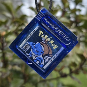 May include: A white ceramic mug with a black handle and the text "But First, Coffee" in a black, handwritten-style font. The mug is on a white surface.