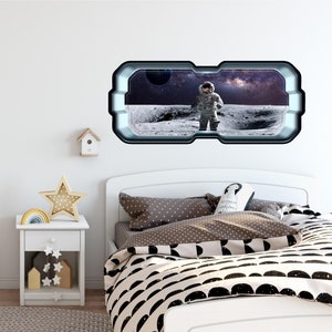 May include: A white wall with a space-themed window sticker featuring an astronaut standing on the moon. The sticker is framed with a silver border and has a realistic look. The sticker is placed above a white bed with a brown and white polka dot pillow and a black and white patterned duvet.