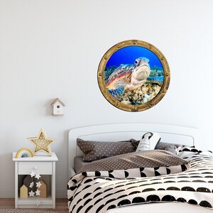 May include: A wall decal featuring a sea turtle peering through a round, gold-framed porthole. The porthole is set against a vibrant blue underwater scene. The turtle is brown and green, with a detailed texture.
