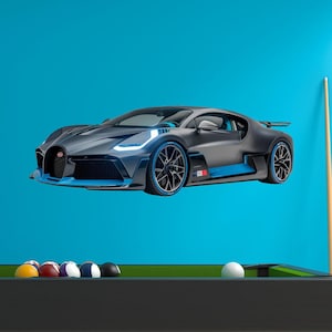 May include: A sleek, dark gray sports car with blue accents and black wheels is featured against a bright blue backdrop. The car has a low profile and aerodynamic design. A pool table with billiard balls and a cue stick is in the foreground.