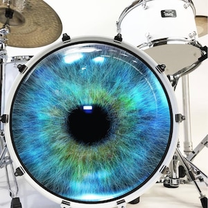 May include: A white drum with a blue eye graphic on the front. The eye is made up of blue, green, and yellow lines.