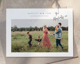 May include: A white card with a photo of a family of four in a field. The text "Happiest New Year two thousand and twenty" is at the top of the card. The text "the Marshalls xo" is written in cursive at the top right corner of the card.
