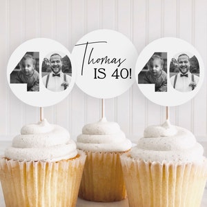 May include: Three cupcakes with white frosting, each topped with a circular paper topper. Two toppers feature the number 40 with black and white photos of a child and an adult. The center topper displays the text Thomas IS 40! in black.