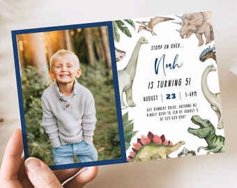May include: A dinosaur-themed birthday invitation with a photo of a young boy. The invitation features a watercolor illustration of various dinosaurs, including a stegosaurus, a brachiosaurus, and a tyrannosaurus rex. The text on the invitation reads "Stomp on over... Noah is turning 5! August 23 1-4PM 631 Kennedy Drive, Bayonne NJ Kindly RSVP to Jen by August 5 at 525-629-9987."