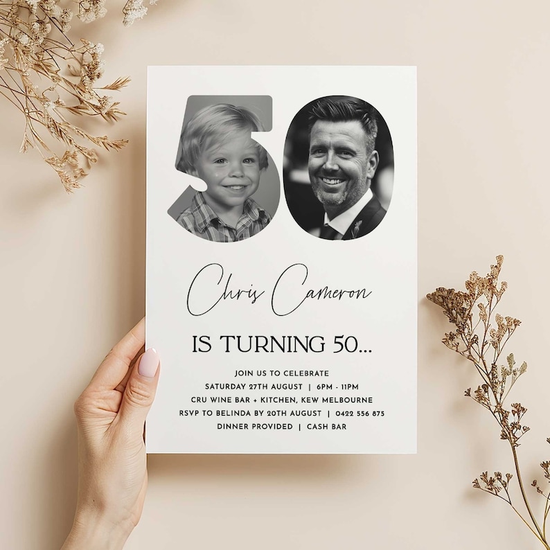 female hand holding a 50th Birthday Invitation against a beige wall with boho elements and dried flowers