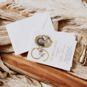 May include: A white card with gold lettering and a floral design. The card says "90 Years Loved" and "Helen Johnson". There is a photo of a woman in the corner of the card.