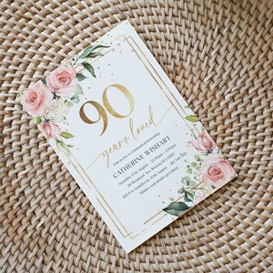 May include: A gold and white invitation card with a floral design and gold glitter. The card reads "90 years loved" and includes the text "Join us for a celebration honoring Catherine Wishart".