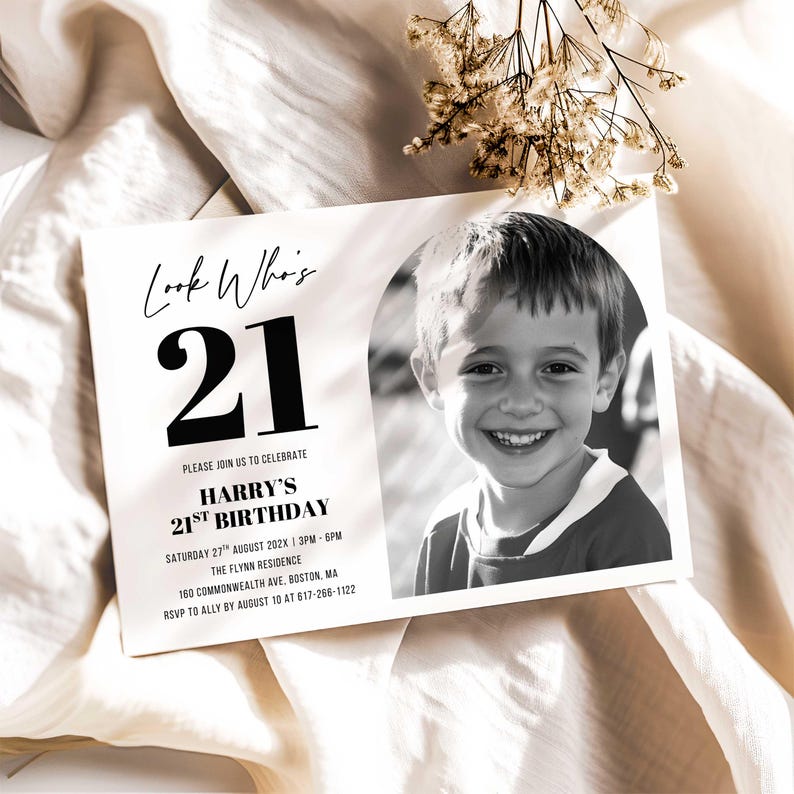 Printed 21st birthday invitation with bold “21” and portrait photo, styled on soft white fabric with dried florals to show layout and print scale.