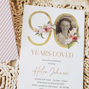 May include: A white invitation card with gold lettering and floral accents. The card reads "90 Years Loved" and includes the text "Join us for a celebration honoring Helen Johnson". The invitation details a party on Saturday, August 27th from 12:30pm to 3:30pm at 28 Westland Ave, Boston MA 02115. RSVP to Jennifer by August 20th at 413-545-0111.