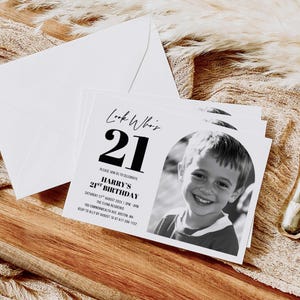 Printed 21st birthday invitation placed on a wooden tabletop with dried botanical accents, displaying full event details and RSVP information.