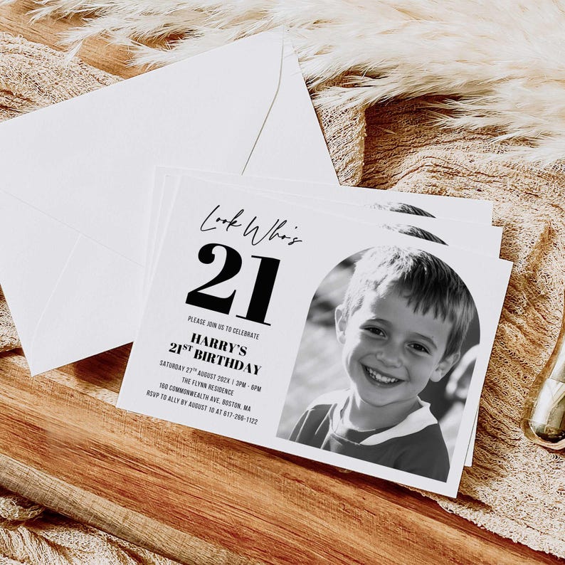 Printed 21st birthday invitation placed on a wooden tabletop with dried botanical accents, displaying full event details and RSVP information.