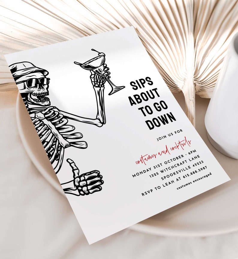 May include: Black and white illustration of a skeleton holding a martini glass. The text "Sips About To Go Down" is written in red. The text below reads "Join us for costumes and cocktails Monday 31st October 6PM 1325 Witchcraft Lane Spooksville 45233 RSVP to Leah at 615.888.5987 costumes encouraged."