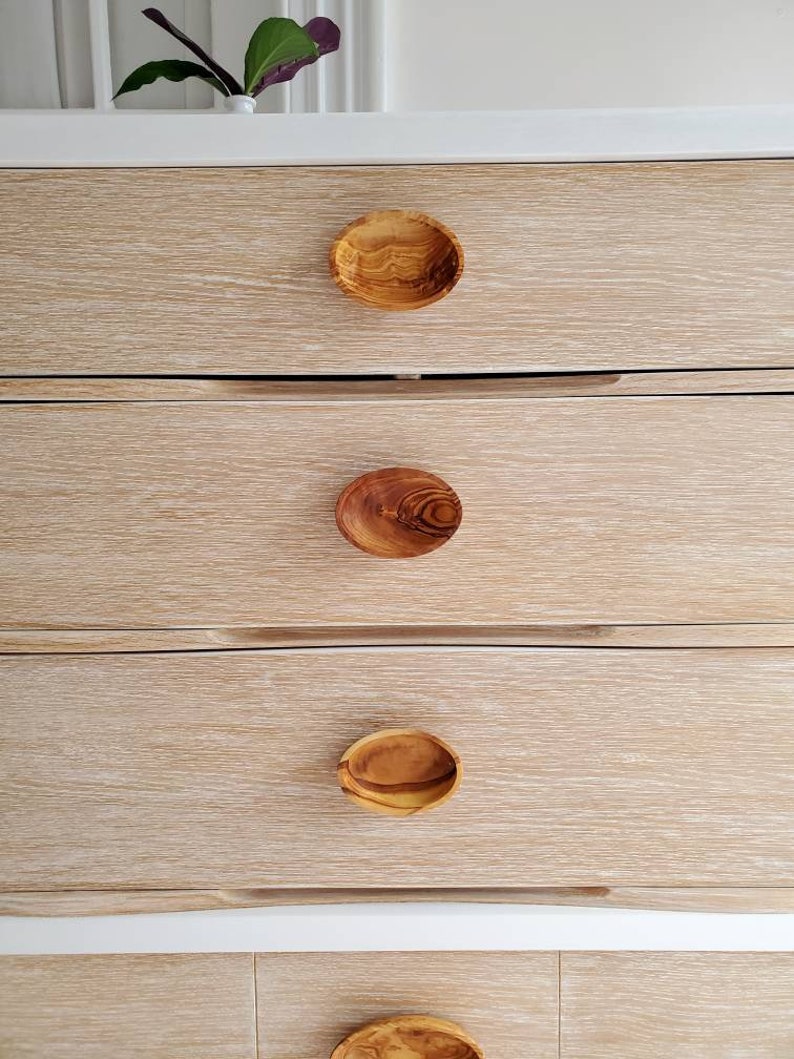 May include: A white dresser with four drawers and wooden knobs. The dresser has a light wood grain finish.