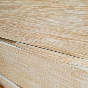 May include: Close-up of a light wood dresser with three drawers. The drawers have a whitewashed finish and a slightly curved edge.