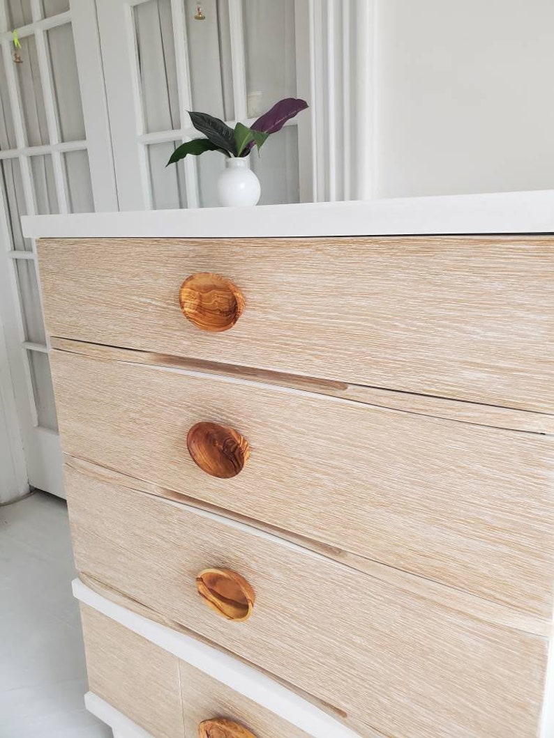 May include: A white dresser with four drawers and wooden knobs. The dresser has a light wood grain finish.