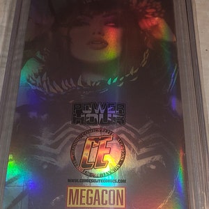 May include: A holographic comic book cover featuring a woman with dark hair and red eyes. The cover has a rainbow iridescent effect and the text "Power Hour Preview Edition #2" and "Black Ops Publishing 2023".