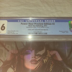May include: A graded comic book with a 9.6 rating. The comic book is titled "Power Hour Preview Edition #2" and is published by Black Ops Publishing in 2023. The comic book is a MegaCon exclusive with a "Virgin" cover.