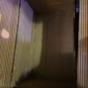 May include: The inside of a vintage striped suitcase with a wooden frame. The lining is made of a striped fabric with black and yellow stripes.