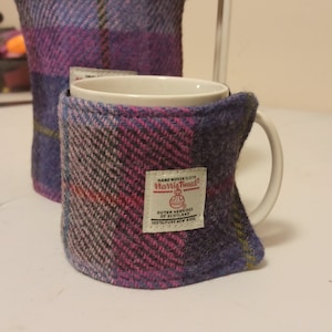 May include: A purple, pink and blue plaid mug cosy with a white label that reads "Hard Woven Cloth Harris Tweed Outer Hebrides of Scotland 100% Pure New Wool".