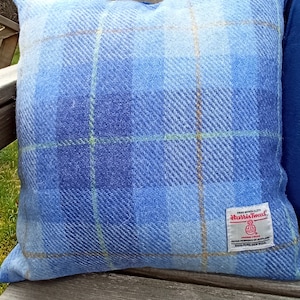Puede incluir: Cojín de sofá azul y blanco a cuadros con una etiqueta de Harris Tweed. La etiqueta dice "Hand Woven Cloth Harris Tweed Outer Hebrides of Scotland 100% Pure New Wool."