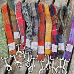 Op de afbeelding: Een verzameling van 10 kleurrijke hondenriemen gemaakt van Harris Tweed stof. Elke riem heeft een zilveren metalen clip en een geweven label met de tekst "Harris Tweed".