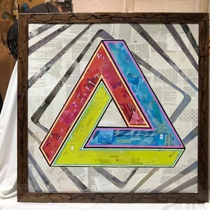 May include: A framed artwork featuring a colorful, optical illusion triangle design. The triangle is made up of overlapping layers of paper with different colors and patterns. The artwork is set against a background of white paper with a subtle gray pattern.