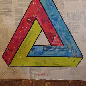 May include: A colorful, optical illusion triangle made of paper, with red, blue, and yellow sections. The triangle is on a white background with a newspaper-like texture.