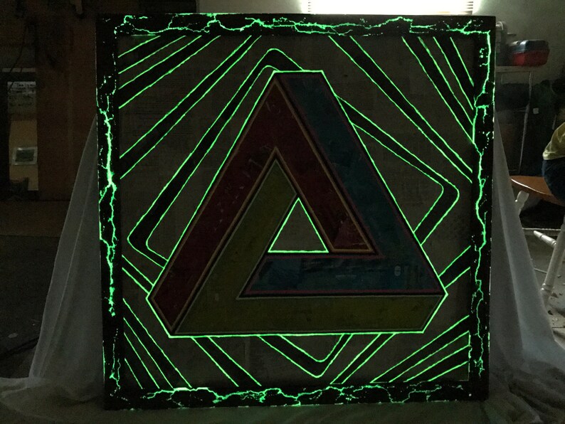 May include: A framed artwork with a green, yellow, red, and blue geometric triangle design. The frame is black and has a green glow around the edges.