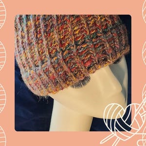 May include: A colorful knitted beanie hat with a multi-colored yarn in shades of red, orange, yellow, green, and brown. The hat is worn on a mannequin head.