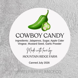 May include: A circular white label featuring a green jalapeno pepper illustration. Text reads: COWBOY CANDY, Ingredients: Jalapenos, Sugar, Apple Cider Vingear, Mustard Seed, Garlic Powder, Made with love by: MOUNTAIN RIDGE FARM, Canned July 2026, PIXELPAPERLANCECO.
