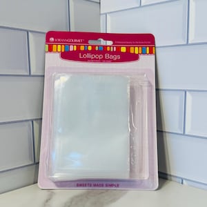 May include: A package of 100 clear plastic lollipop bags, 3.5 inches in size. The package is pink and white with the text "Lollipop Bags" and "Sweets Made Simple".