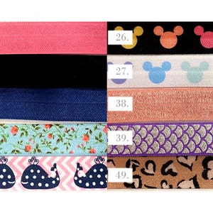 May include: A set of ten colorful elastic hair ties with different patterns, including pink, black, blue, floral, whale, Mickey Mouse, glitter, and hearts. The numbers 2, 8, 9, 16, 24, 26, 27, 38, 39, and 49 are printed on the elastic bands.